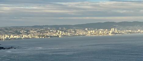 A coastal cityscape with a wide beach and a densely built urban area in the background.