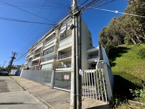 Un immeuble résidentiel à plusieurs étages, doté de balcons, d’une entrée sécurisée et de lignes électriques apparentes.