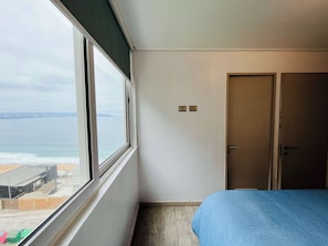 Una habitación con un ventanal, una cama, una puerta e interruptor de luz en la pared.