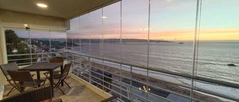 A balcony with a view of the sea and distant cityscape.