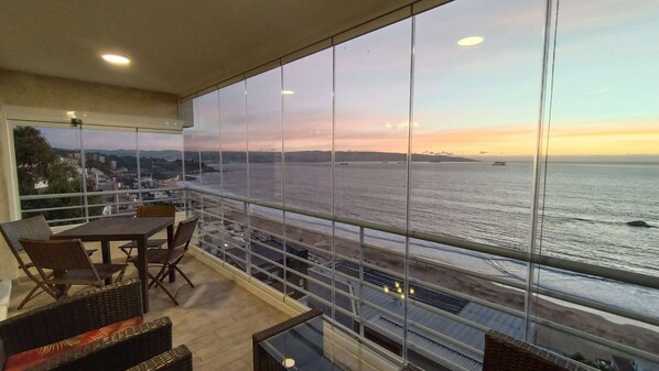 A balcony with a view of the sea and distant cityscape.
