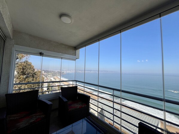 Un balcon offrant une vue dégagée sur l’océan et sur les bâtiments d’une ville lointaine.