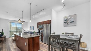 Una cocina moderna con una isla central, electrodomésticos de acero inoxidable y una zona de comedor con una mesa y sillas de madera.