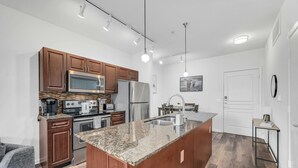Una cocina moderna con armarios de madera, electrodomésticos de acero inoxidable y una isla con encimera de granito.
