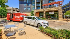 Un SUV blanco estacionado frente a un edificio con un cartel que dice 'coffee + crisps'.