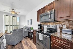 A modern kitchen with dark wood cabinets, stainless steel appliances, and a granite countertop. - Magic Haven @ The Domain - ATX (Austin)