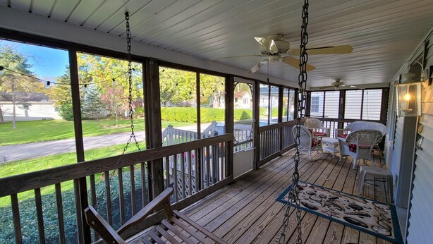 A wooden deck with a swing chair, a bench, and a table with a placemat. - 645 Sycamore in Lakeside (Lakeside)