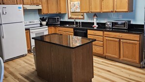 A modern kitchen with wooden cabinets, a central island, and built-in appliances. - 645 Sycamore in Lakeside (Lakeside)