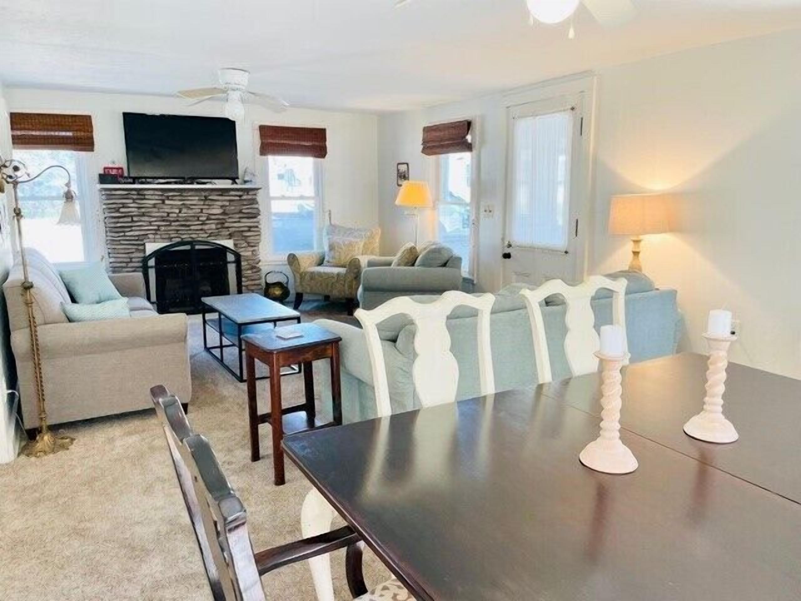 A living room with a fireplace, sofa, armchair, and a dining table.