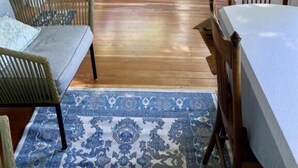 A sunroom with a wooden floor, a white bench, a table, and a ceiling fan. - 502 Walnut in Lakeside (Lakeside)