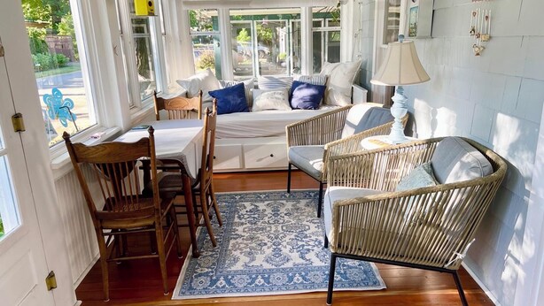 A cozy room with a bed, two wicker chairs, a table, and a rug. - 502 Walnut in Lakeside (Lakeside)