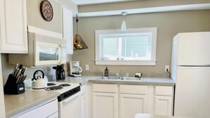 A compact kitchen with white cabinets, a stove, a sink, and a refrigerator. - 502 Walnut in Lakeside (Lakeside)
