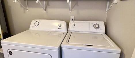 Un área de lavandería con dos lavadoras de carga frontal y dos cestos apilados en un estante superior.