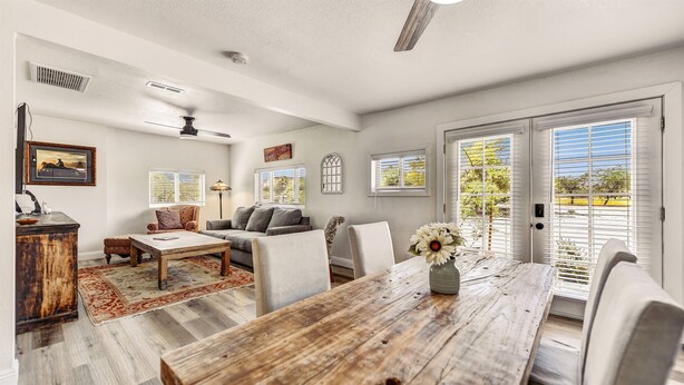 A spacious living room with a wooden dining table, comfortable seating, and large windows with blinds. - Charming Casita in Cave Creek (Cave Creek)