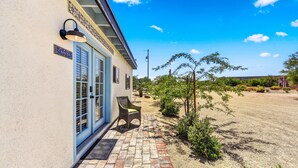 A building with a blue door, a sign reading "CASITA," and a small patio area with a chair and a table. - Charming Casita in Cave Creek (Cave Creek)