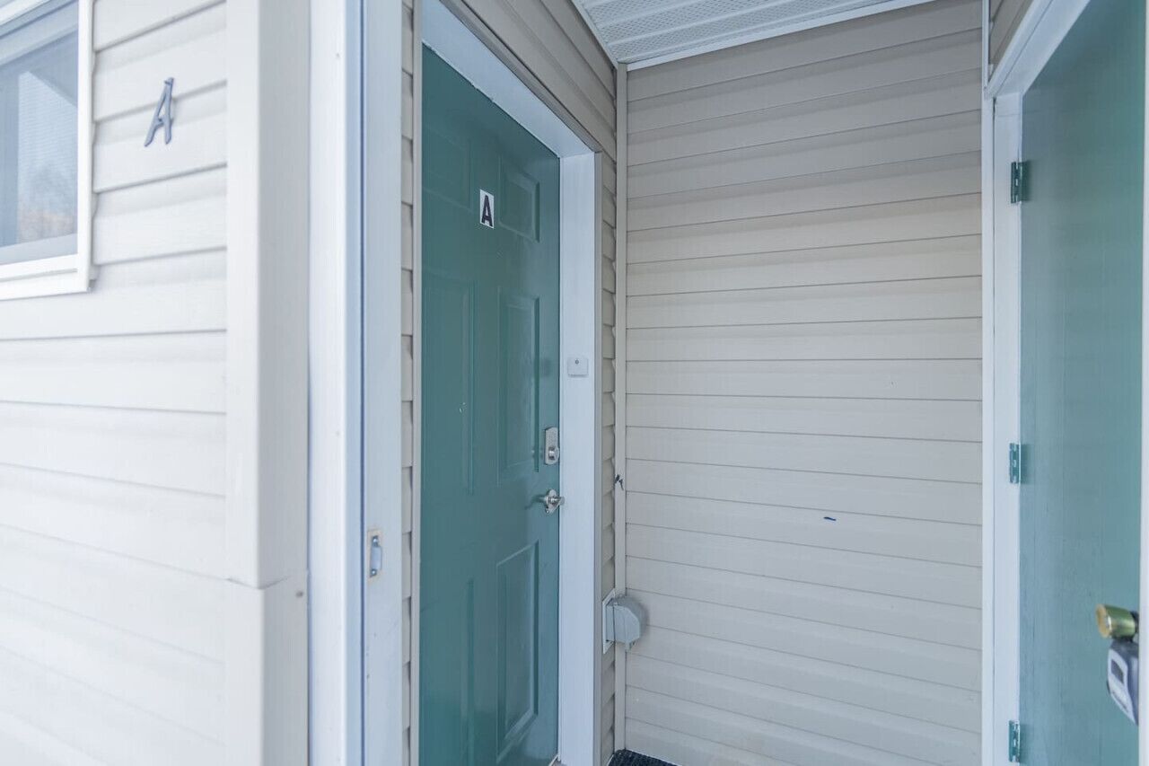 A house with a teal door and a white window.