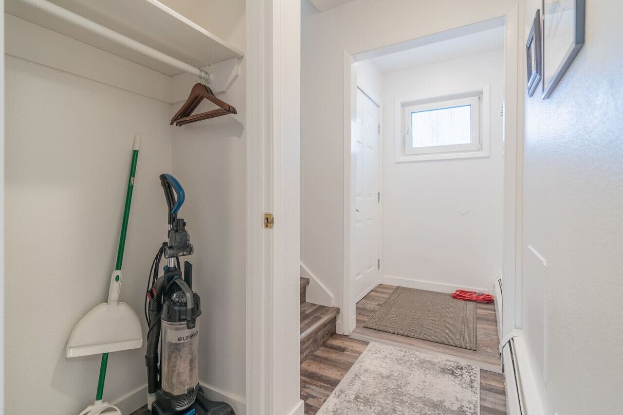 Un couloir avec un aspirateur, un balai et une serpillière.