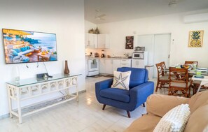 Relax in this stylish living room with a large flat-screen TV, comfortable seating, and a dining area for four.