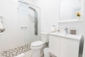 A modern bathroom with a shower, toilet, and sink. - Family House w. Pool, Parking & Basketball Court! In Rainforest!10 min to beach! (Rio Grande)