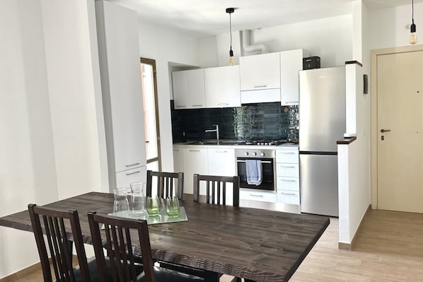 A modern kitchen with white cabinets, a black backsplash, and stainless steel appliances.