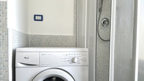 A Whirlpool washer in a bathroom with a shower door and tiled walls. - S342 - Sirolo, comfortable three-room apartment near the center (Sirolo)