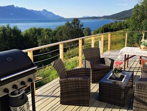 Eine Terrasse mit Korbmöbeln, einem Grill und einem Tisch mit Spitze.
