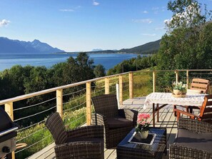 Eine Terrasse mit Korbmöbeln, einem Tisch mit weißer Tischdecke und einem Blumentopf.