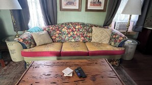 A cozy living room with a floral-patterned sofa, a wooden coffee table, and two framed pictures on the wall. -  Sunday Haus- 2 blocks from Main Street! Sleeps 4 (Fredericksburg)