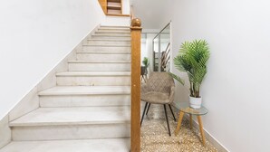 Μια σκάλα με ξύλινο κάγκελο και μια καρέκλα με ένα τραπεζάκι από γυαλί δίπλα της.