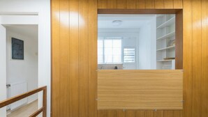 Μια πόρτα με ξύλινο πλαίσιο και έναν καθρέφτη, ένα λευκό καλοριφέρ και ένα δάπεδο με πλακάκια.
