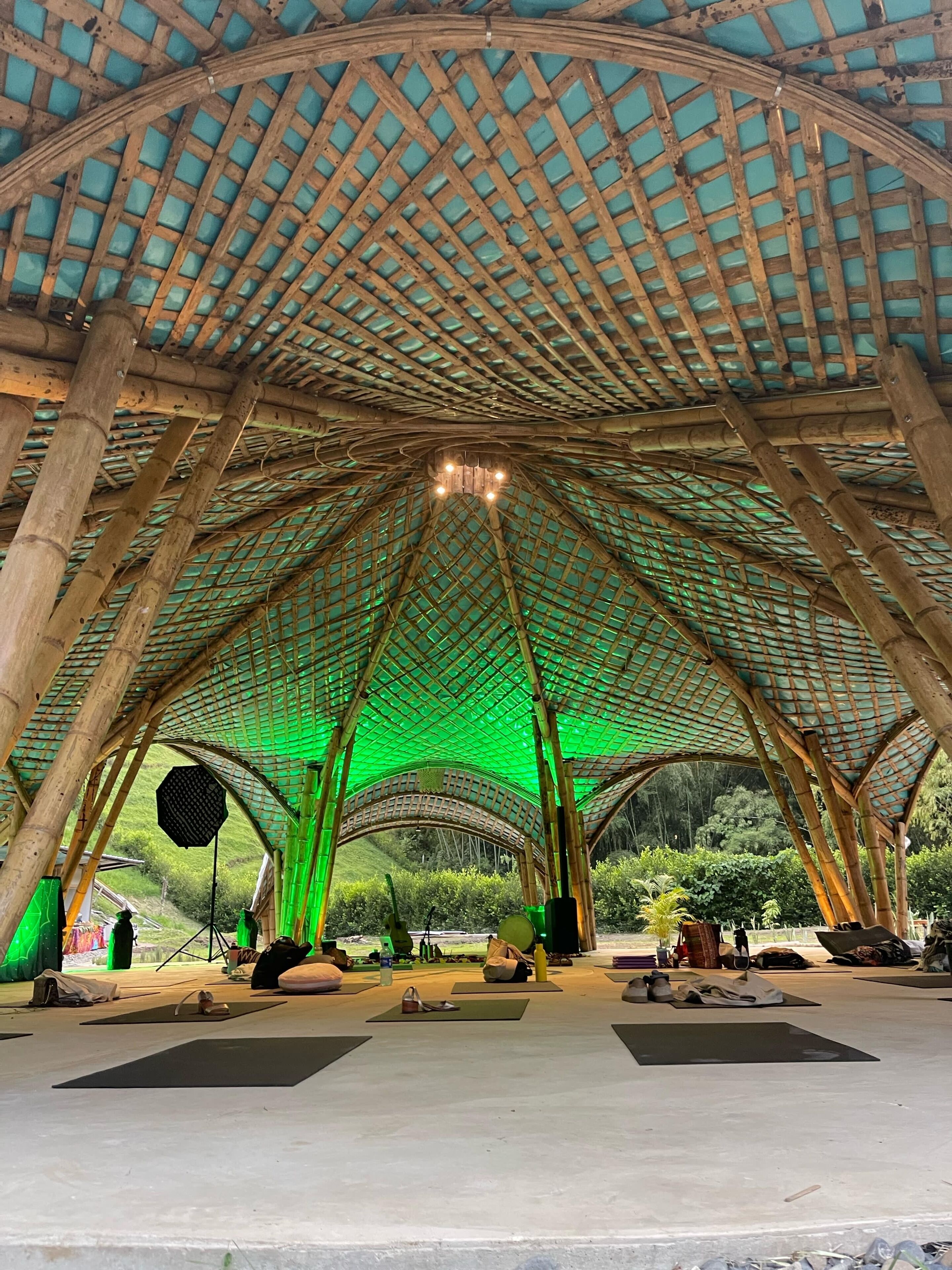 An indoor space with a high, arched bamboo ceiling and a green-lit interior.