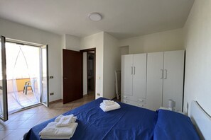Un dormitorio con cama, armario y baño visible a través de una puerta abierta.