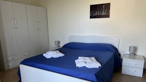 Une chambre à coucher avec un lit, une armoire blanche et une table de chevet avec une lampe.