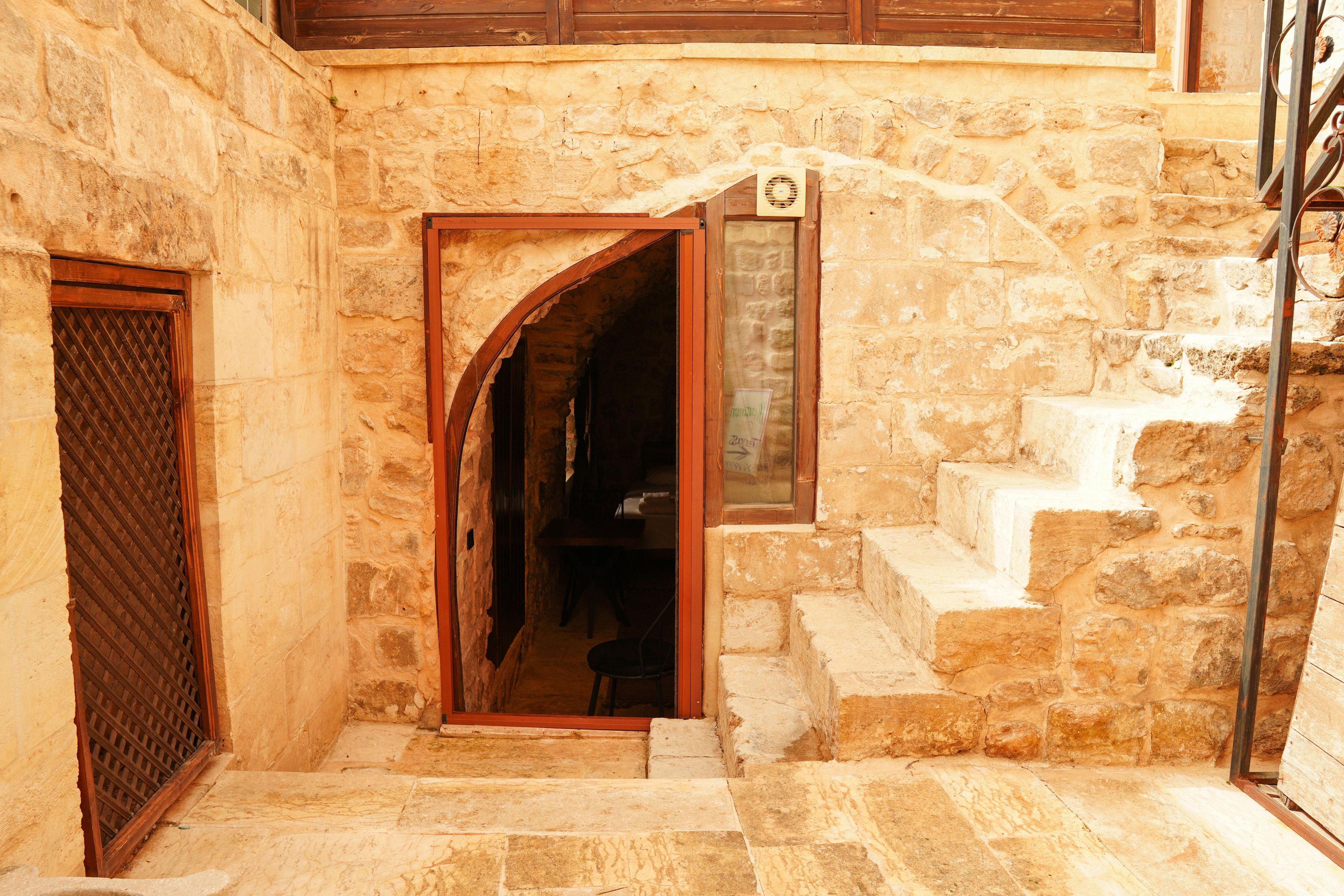 Una scala in pietra che conduce a una porta in legno con una griglia metallica.