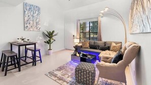 A modern living room with a sofa, coffee table, and a dining area with stools. - ~The Hidden Gem~ King Bed and Hot Tub!

 (Chandler)