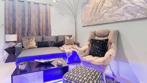 A modern living room with a sofa, a chair, a coffee table, and a large abstract painting on the wall. - ~The Hidden Gem~ King Bed and Hot Tub!

 (Chandler)