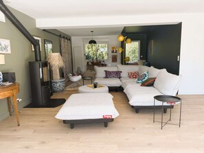 Relax in this stylish living space with a large sofa, colorful throw pillows, and a cozy pouf.