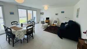 A dining area with a table and chairs, a dark-colored sofa, and a small rug. - 3-room town center, enclosed garden, 150m from the beach (ST PIERRE QUIBERON)