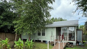A small, single-story house with a porch and a wooden deck. - Artist studio with comfy living accommodations. (Bay St. Louis)