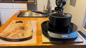 A kitchen counter with a precision induction cooktop, a wooden cutting board, and a kettle. - Artist studio with comfy living accommodations. (Bay St. Louis)