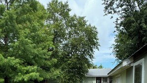 A residential property with a well-maintained lawn, a brick pathway leading to the front door, and a wooden fence surrounding the yard. - Artist studio with comfy living accommodations. (Bay St. Louis)