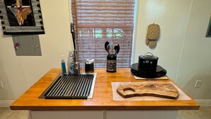 A kitchen island with a wooden countertop, a built-in sink, and a cutting board. - Artist studio with comfy living accommodations. (Bay St. Louis)