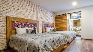 Habitación de hotel con dos camas, pared de ladrillo y suelo de madera.