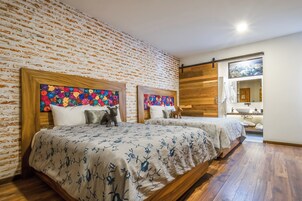Habitación de hotel con dos camas, pared de ladrillo y suelo de madera.