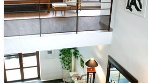 Un vaste espace de vie à plusieurs niveaux, doté d’un balcon, d’un coin salon et d’un escalier.