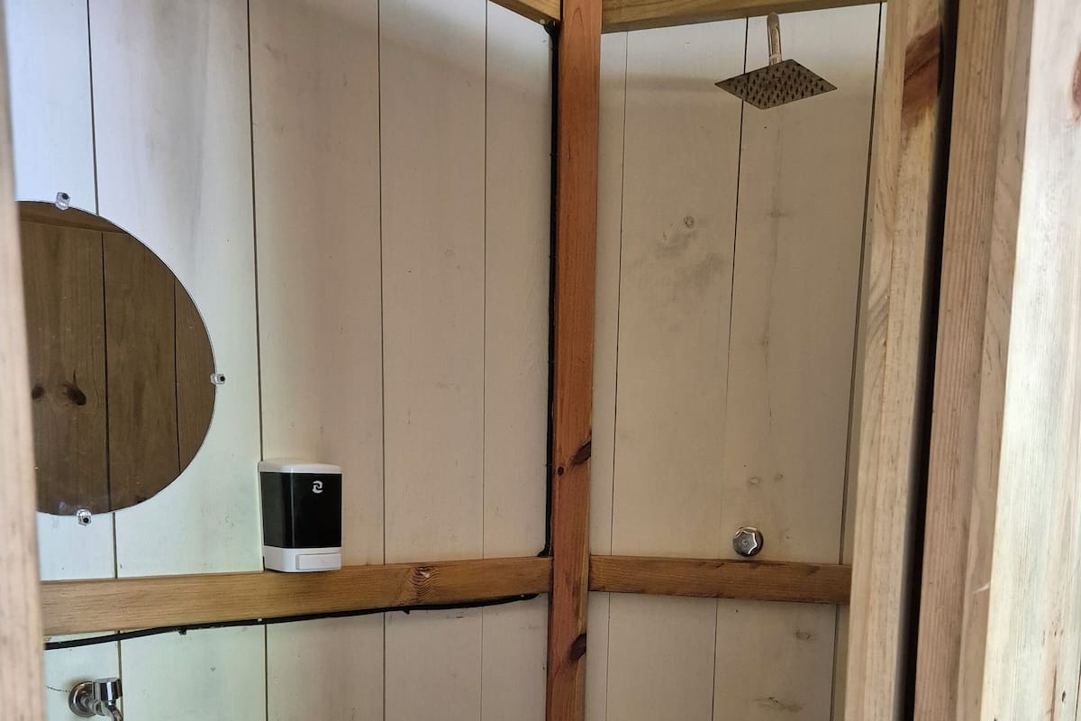 A bathroom with a wooden vanity, a sink, and a shower area.