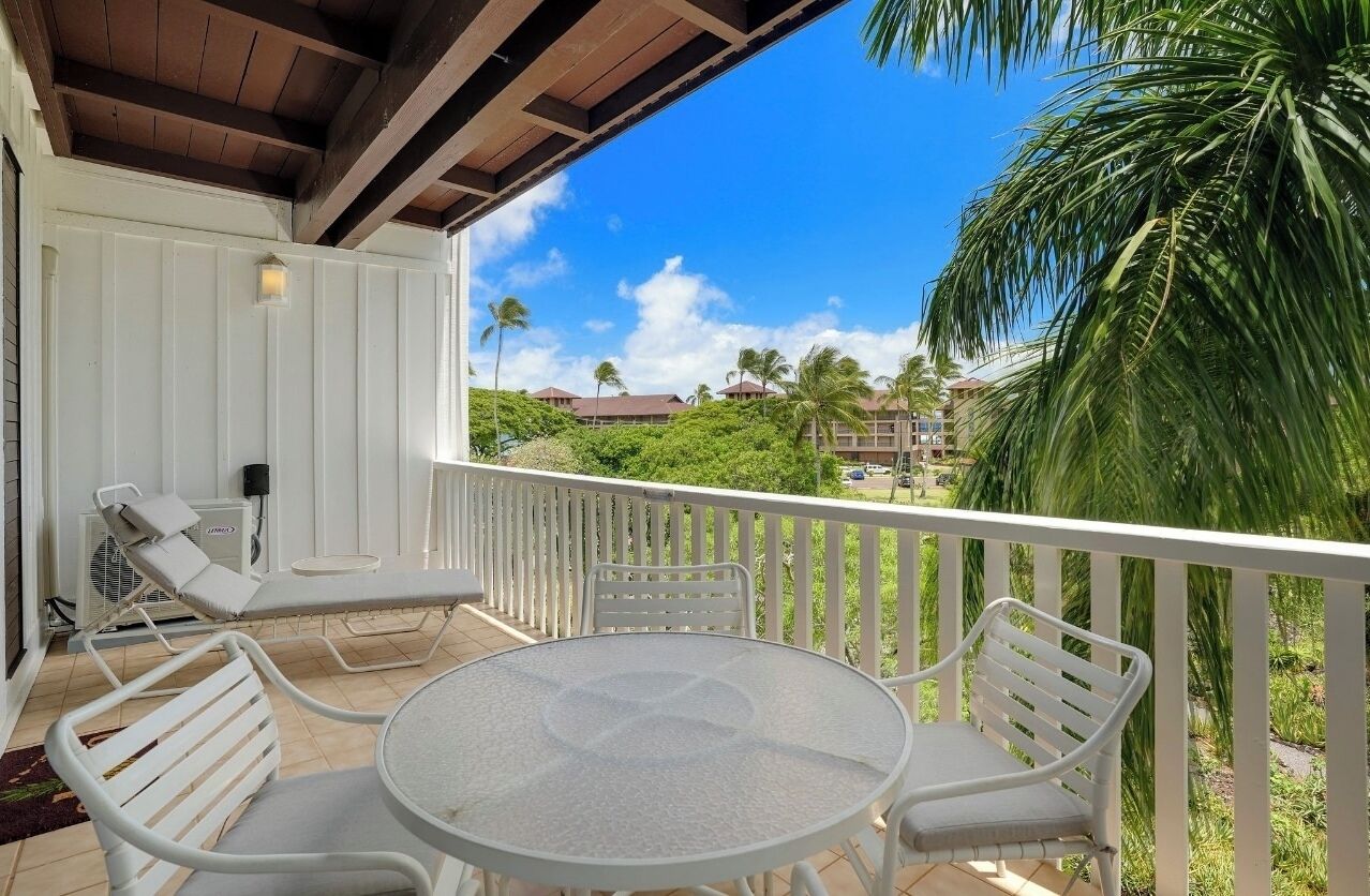 A balcony with a white railing, a round table, and two white lounge chairs.