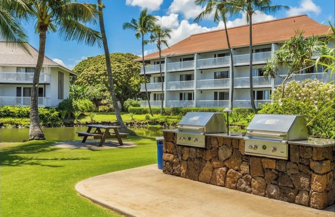 Um hotel com área de churrasco de pedra, mesa para piquenique e piscina.