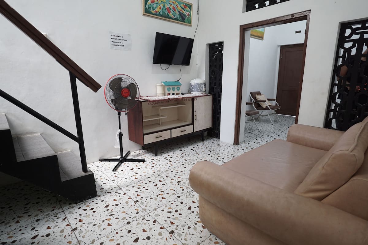 Ein Wohnzimmer mit einer Couch, einem Fernseher, einem Ventilator und einer Treppe.