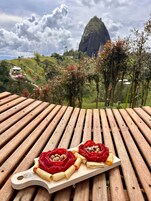 Una mesa de madera con un plato de comida y una vista panorámica de una montaña al fondo.